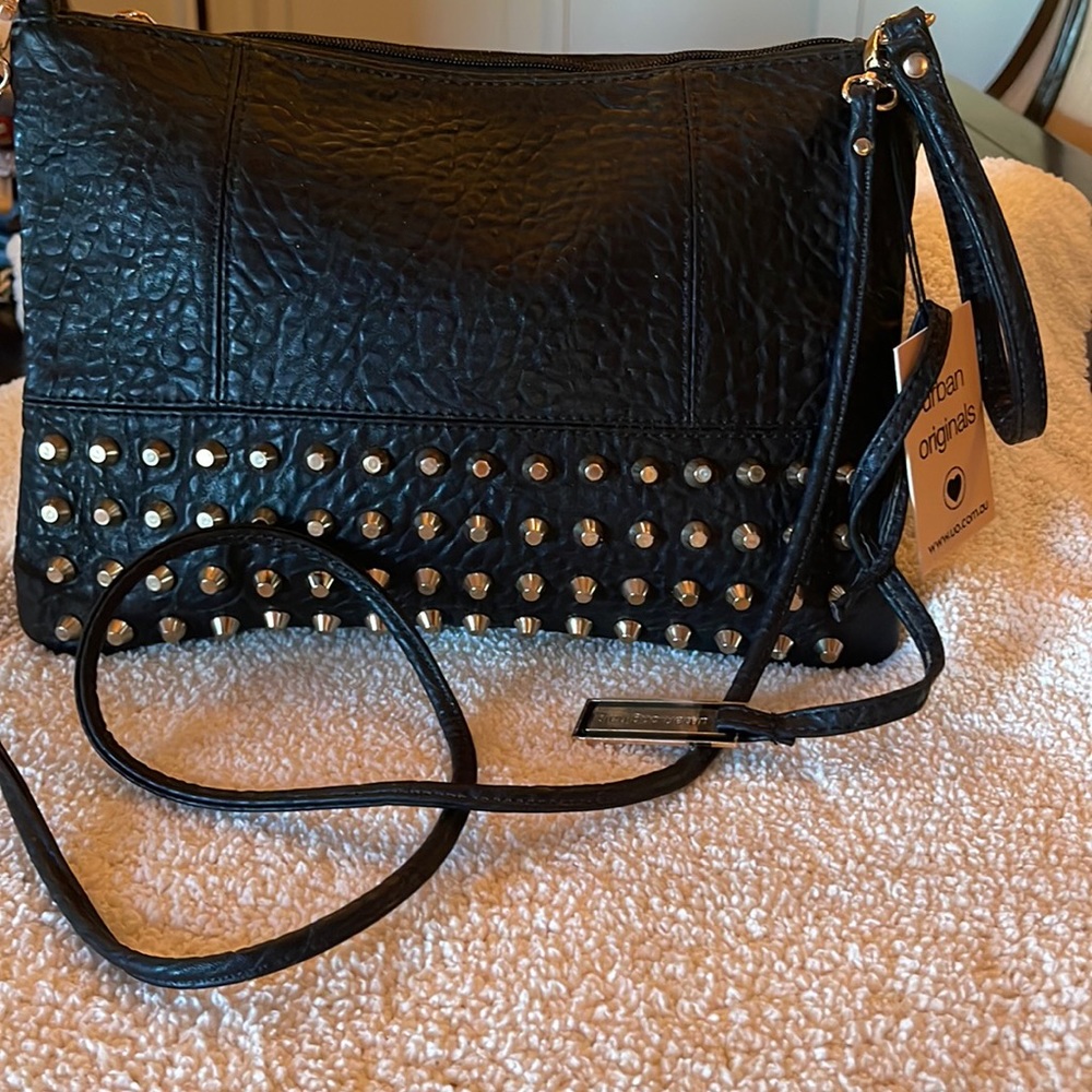 Black grommet vegan leather crossbody bag that has wrist holder